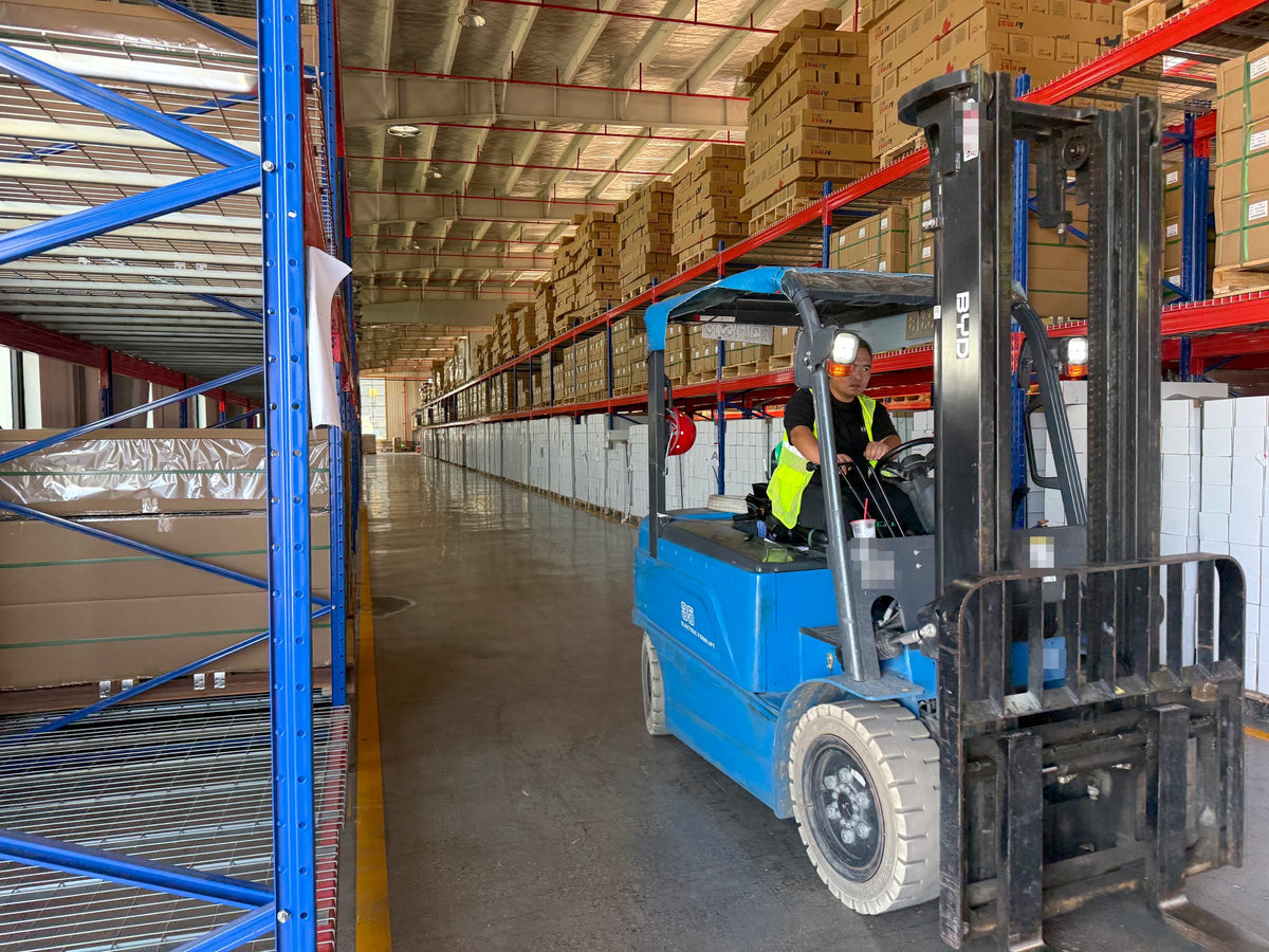 Forklift moving packed film rolls in the factory warehouse